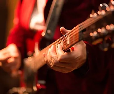 Close-up of hands playing an acoustic guitar under stage light