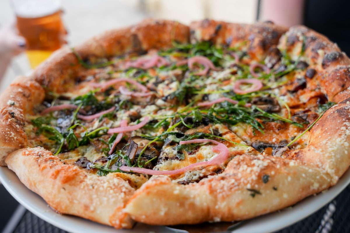 Flatbread pizza topped with arugula and pickled red onion